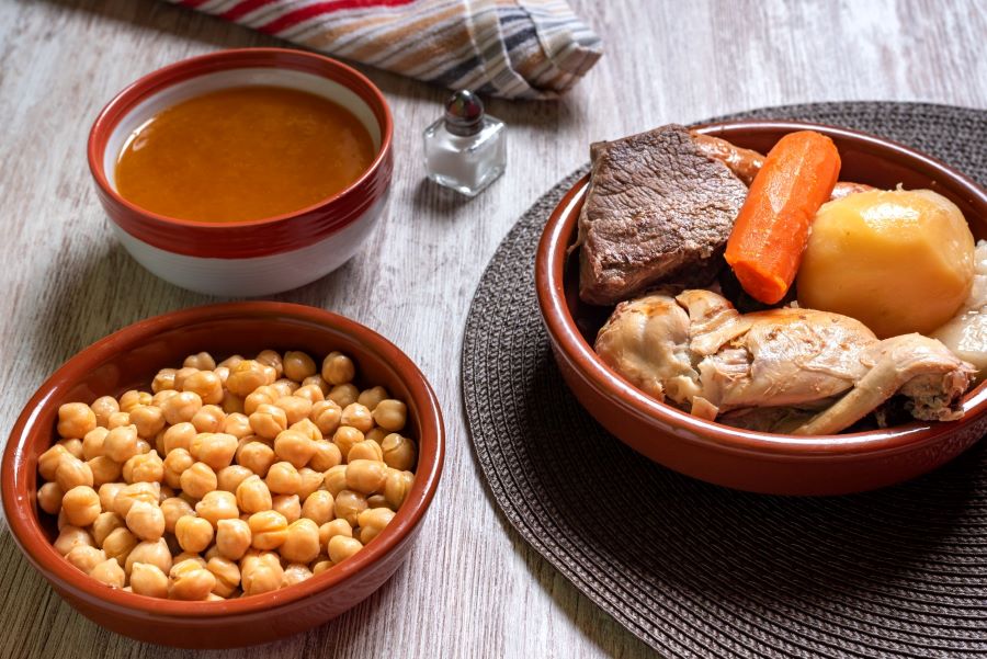 Image of a complete cooked with three bowls: chickpeas, soup and meat.