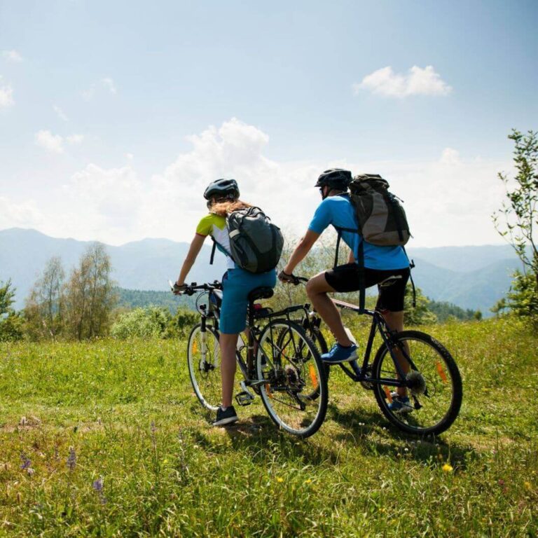 Rutas en bicicleta. Con dos cicloturistas con bicicletas de montaña sobre una colina admirando el paisaje.